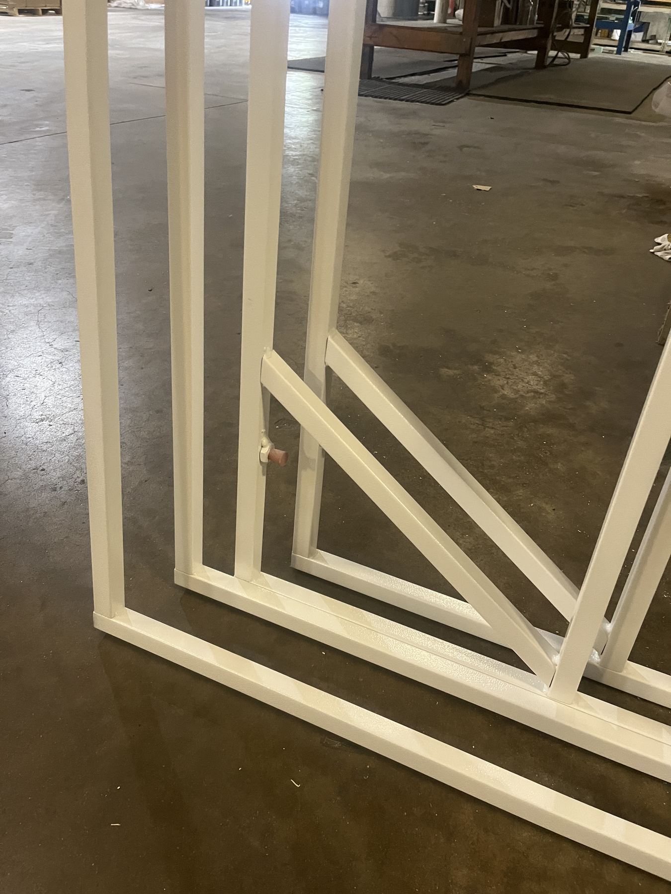 A large welded frame finished in cream powder coat, staged in the shop